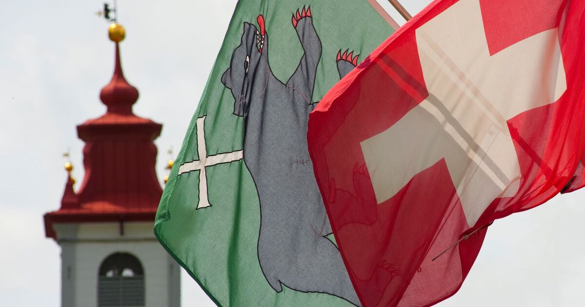 Vibrant Swiss flags fluttering near a historic church tower. Perfect for travel themes.