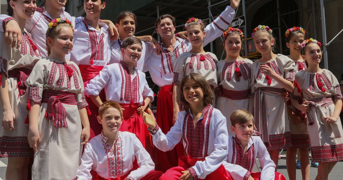 Joyful group at a cultural dance parade in New York, featuring traditional costumes and festive spirit.