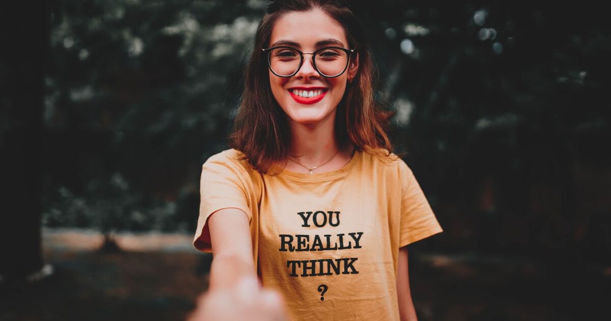 Portrait of a smiling woman with eyeglasses and yellow t-shirt outdoors.