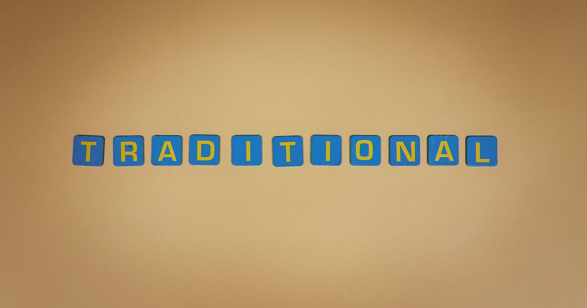 Blue letter tiles spell 'TRADITIONAL' against a warm brown backdrop.