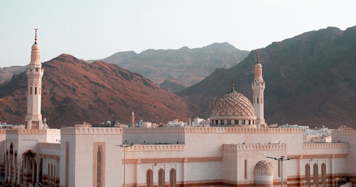 Beautiful mosque with minarets stands against rugged mountain landscape, Saudi Arabia.
