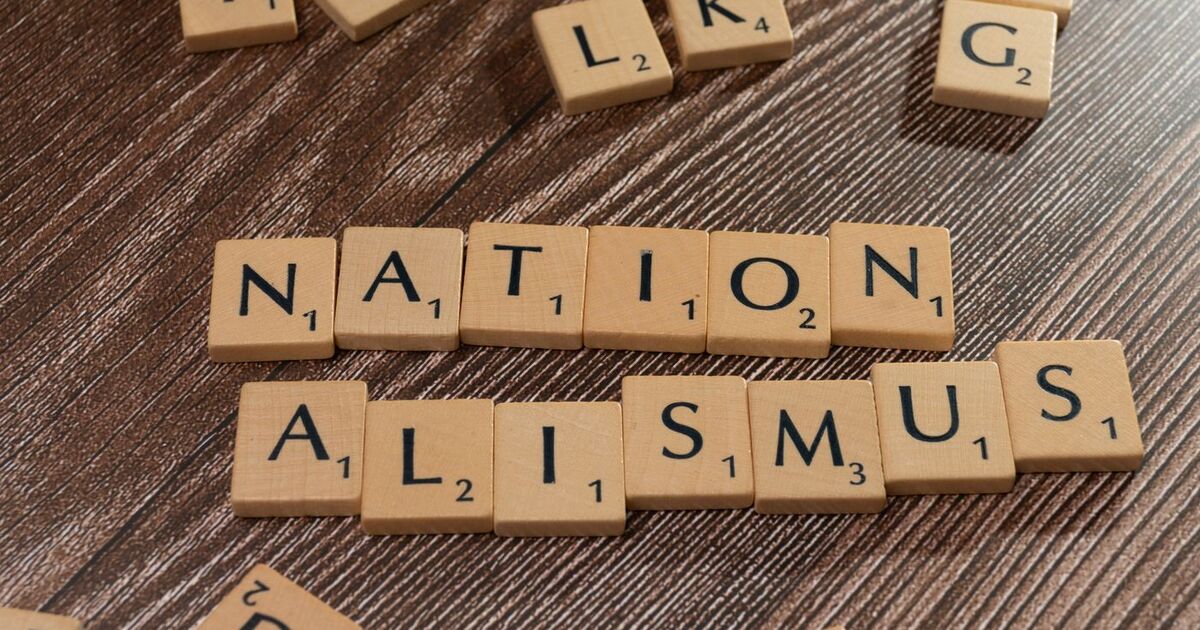 Scrabble tiles spelling 'Nationalismus' on a wooden surface, emphasizing patriotism and language concepts.