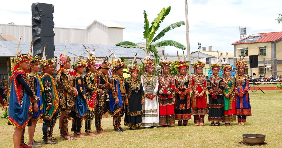 Group of people in colorful traditional attire standing outdoors during a cultural ceremony.
