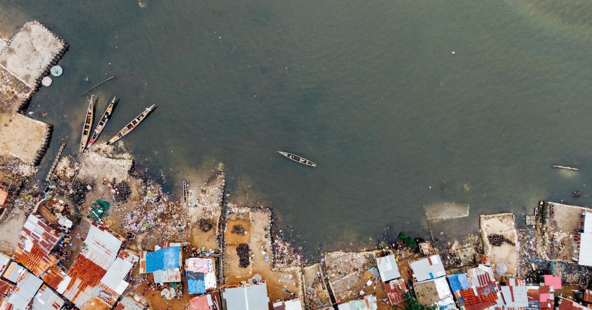 Aerial view capturing a coastal settlement with boats on a calm shore, showcasing vibrant roofs.