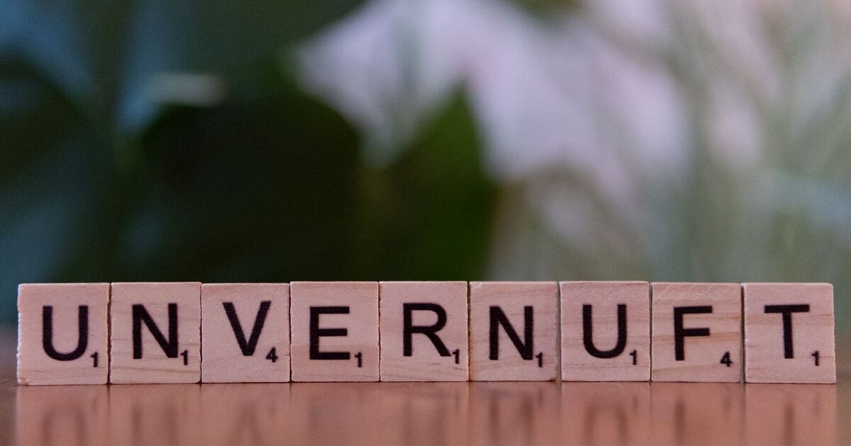 Close-up of wooden Scrabble tiles spelling 'UNVERNUFT' against a blurred background.