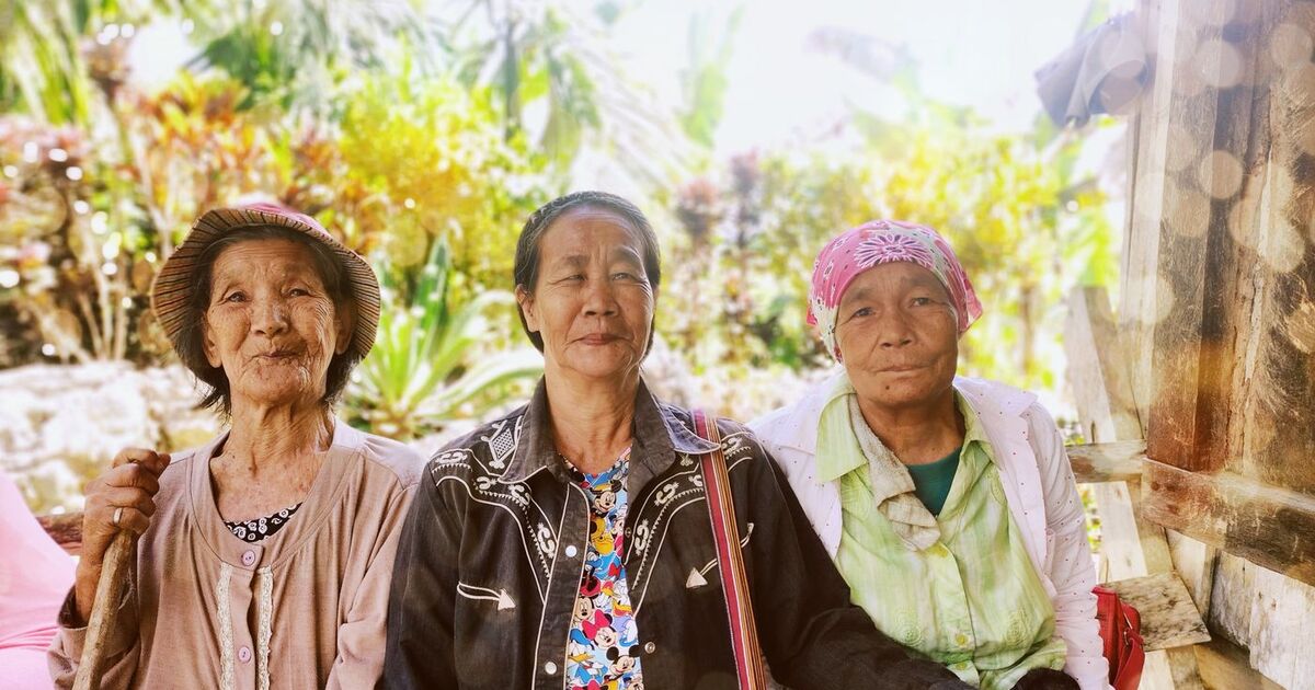 Three senior women smiling outdoors in Cordillera, Philippines.