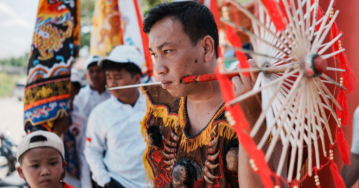 Traditional event in Singkawang, featuring a man with an umbrella in ceremonial attire.