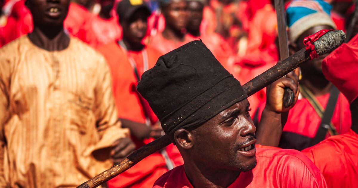 Colorful parade featuring adults in traditional red clothing celebrating a cultural festival.
