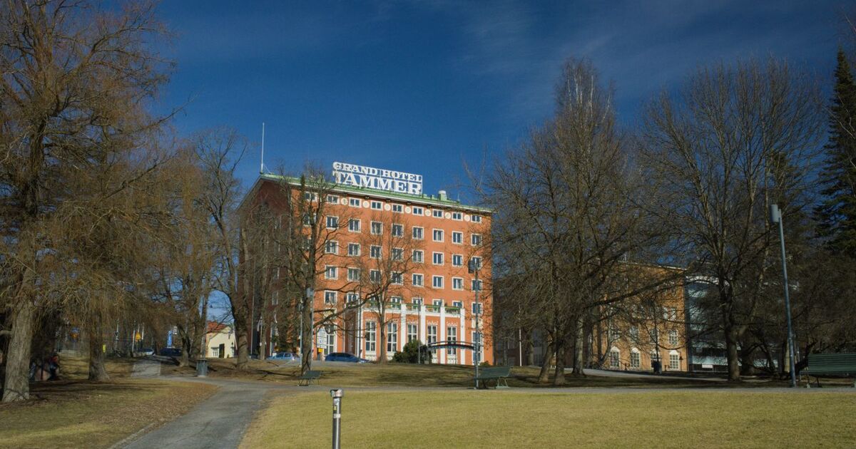 Front view of Grand Hotel Tammer surrounded by trees on a sunny day in Tampere, Finland.