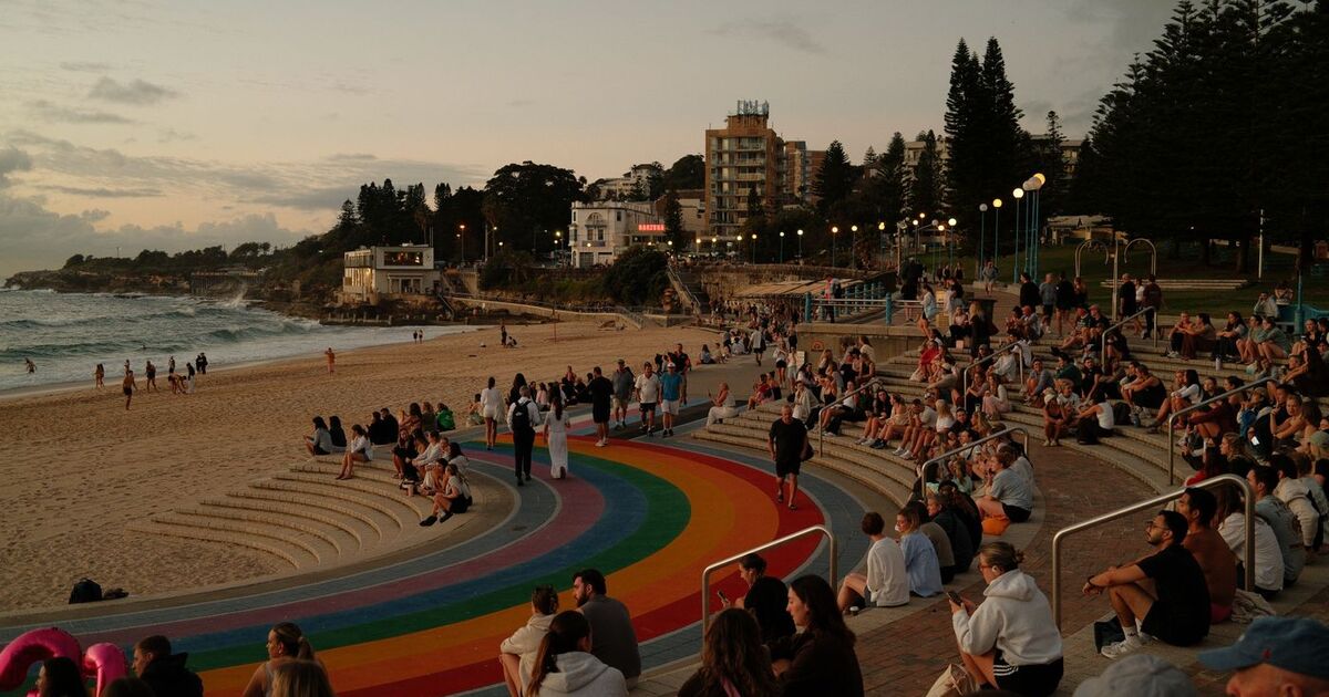 Vibrant Bondi Beach with crowds enjoying a beautiful sunset in Sydney, Australia.