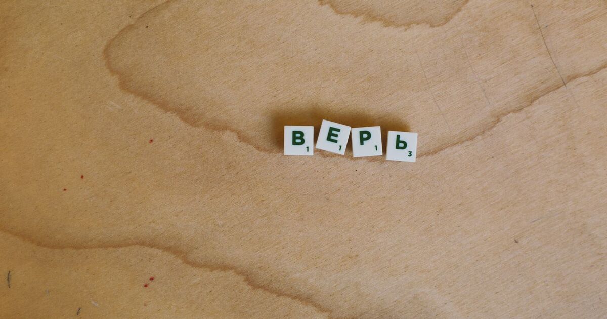 Scrabble tiles with Cyrillic letters spelling 'верь' displayed on a wooden surface.