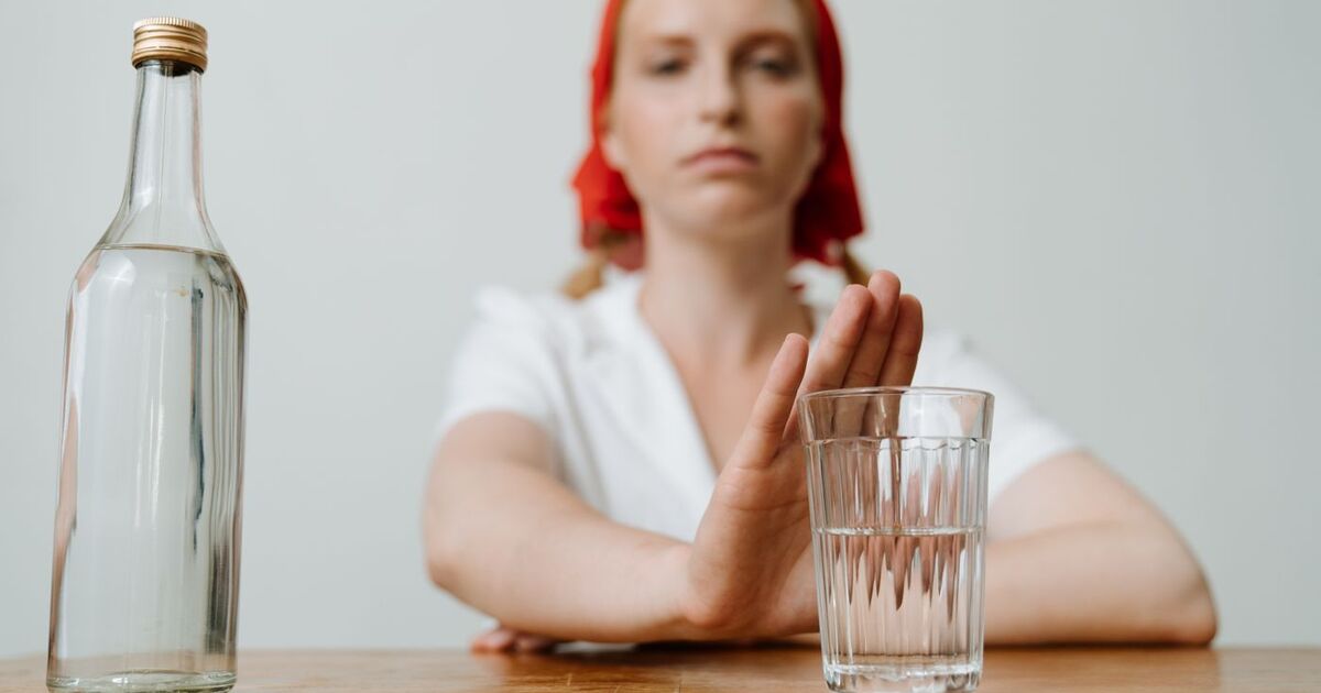 A woman with a red kerchief rejects a glass of alcohol, symbolizing sobriety or refusal.