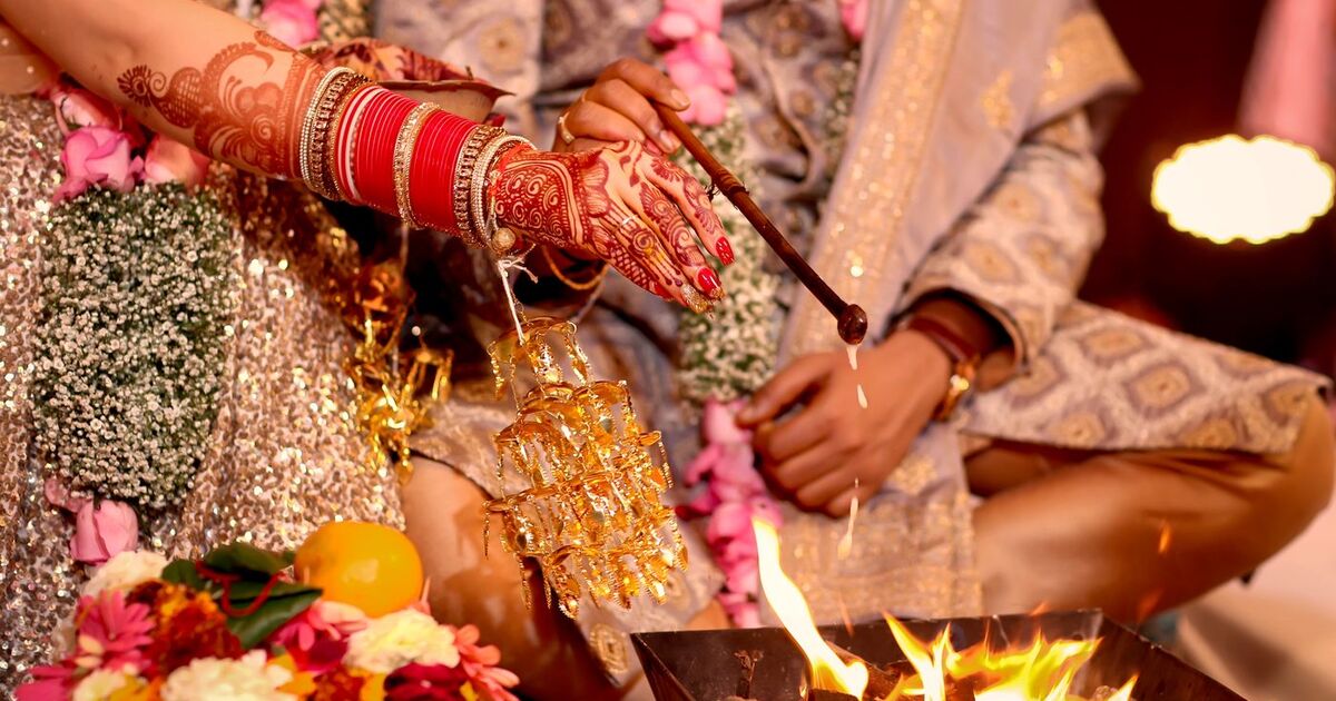 Close-up of traditional Hindu wedding ritual with henna hands over fire.
